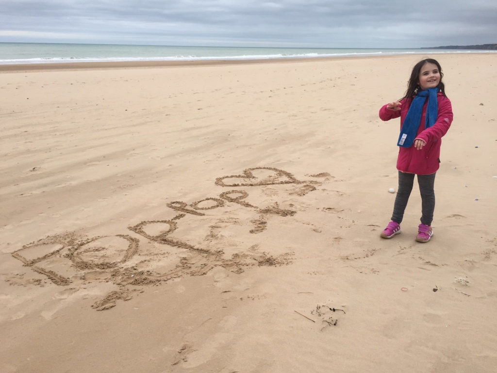 little girl drawing in the sand, great-granddaughter of WWII veteran, the beaches of normandy, beaches of normandy, D-Day
