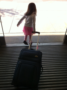 little girl in an airport with a suitcase